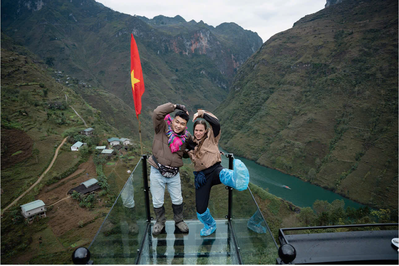 Travelers enjoying a 2026 Ha Giang Loop tour with professional Easy Riders. They are dressed in trekking gear with a background of the Northern Vietnam highlands. 