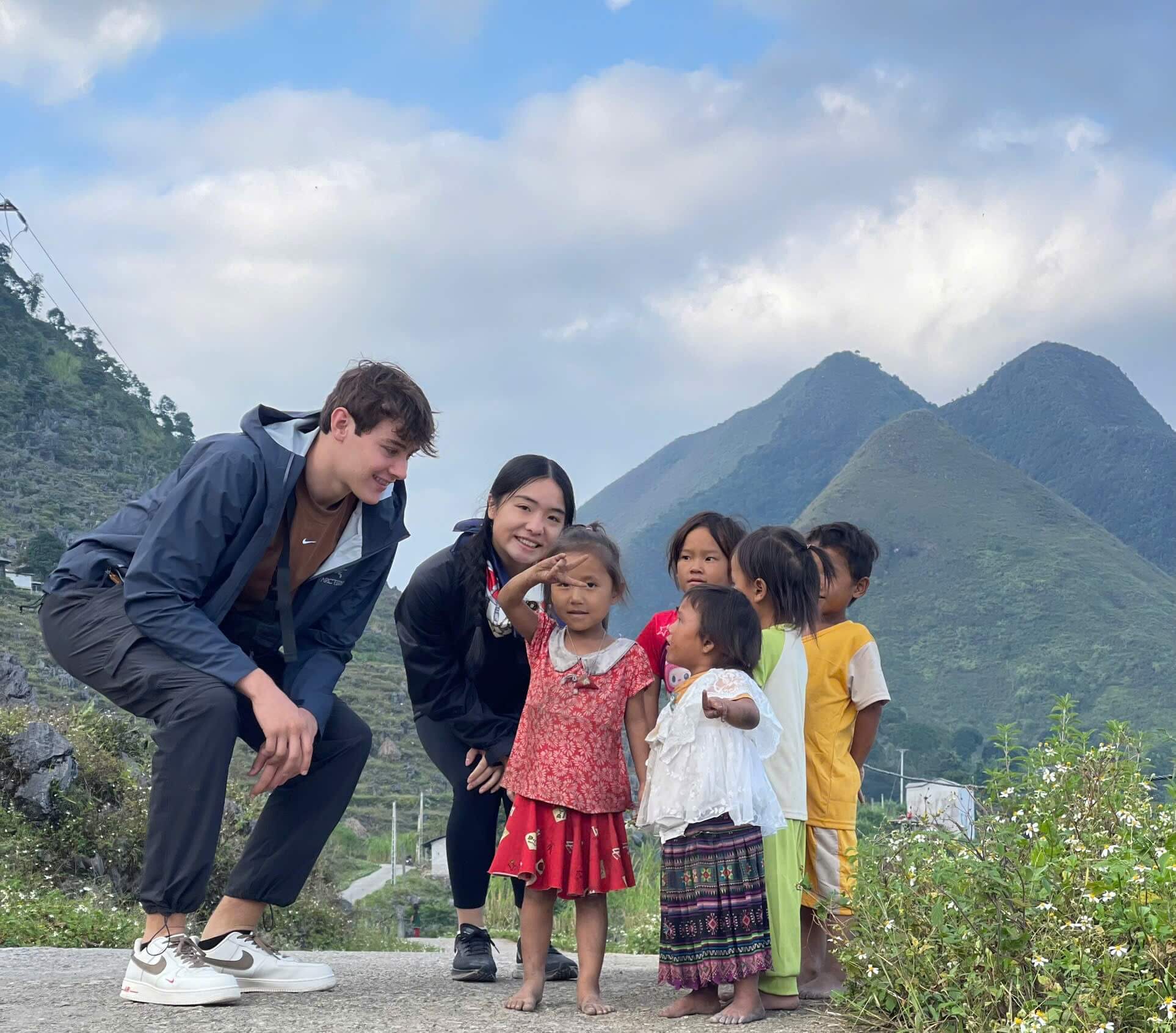 Two travelers interacting responsibly with a group of local ethnic children in a village, a key part of our Ha Giang donations guide