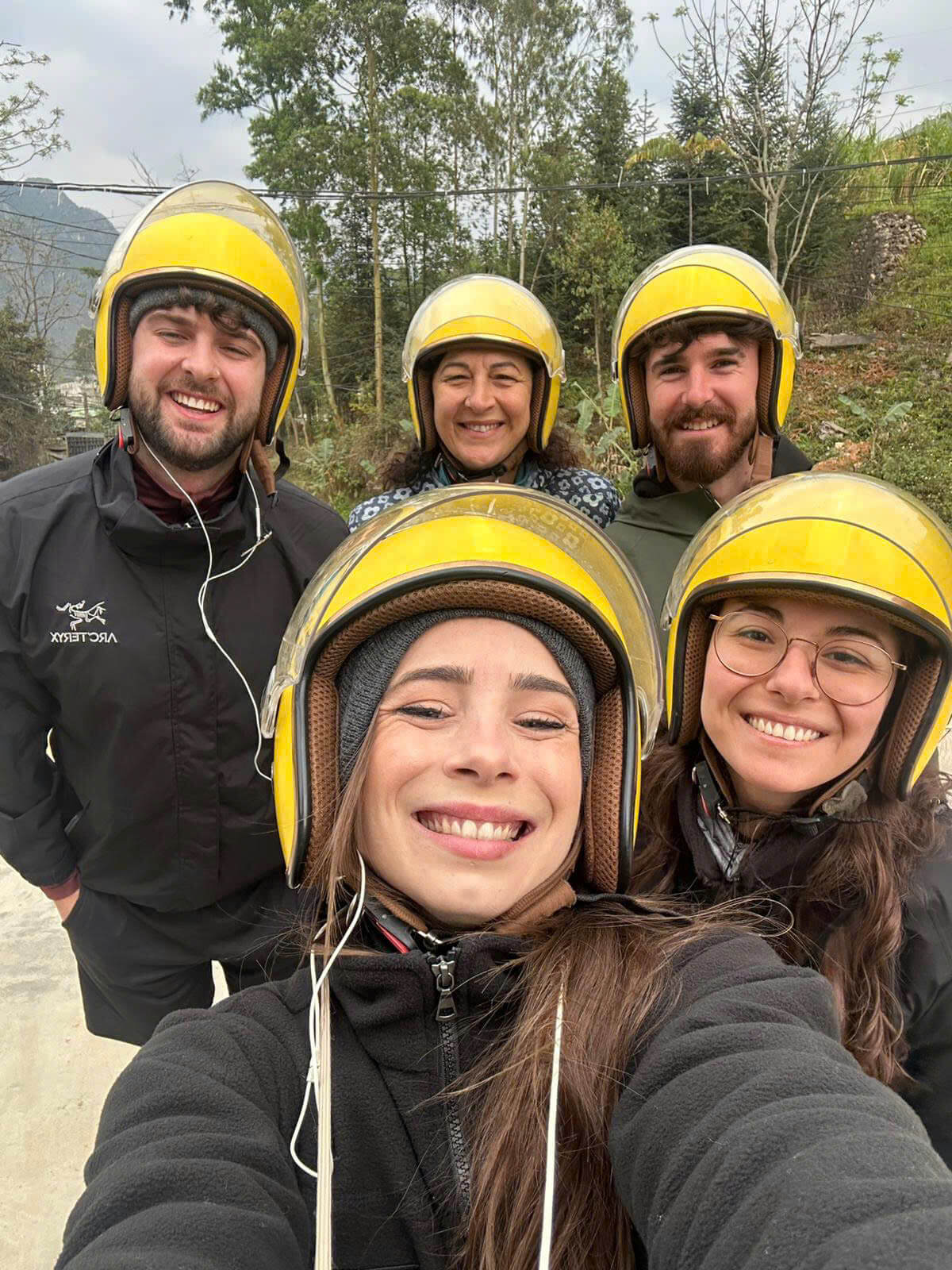 Group of happy tourists wearing matching yellow safety helmets ready for their Ha Giang Loop motorbike adventure