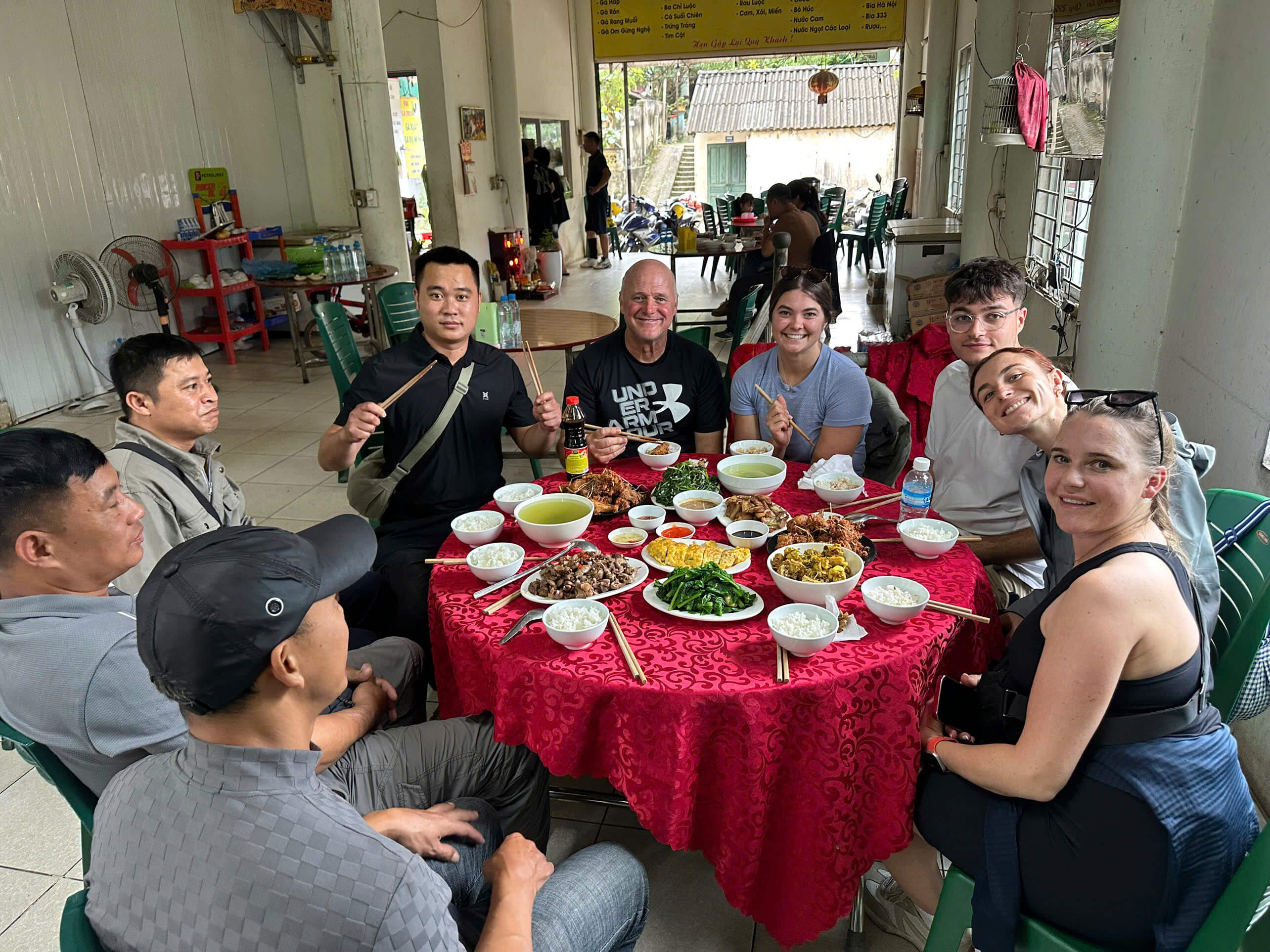 Travelers and Easy Riders enjoying a delicious, authentic Vietnamese family meal together during the Cao Bang Loop adventure.
