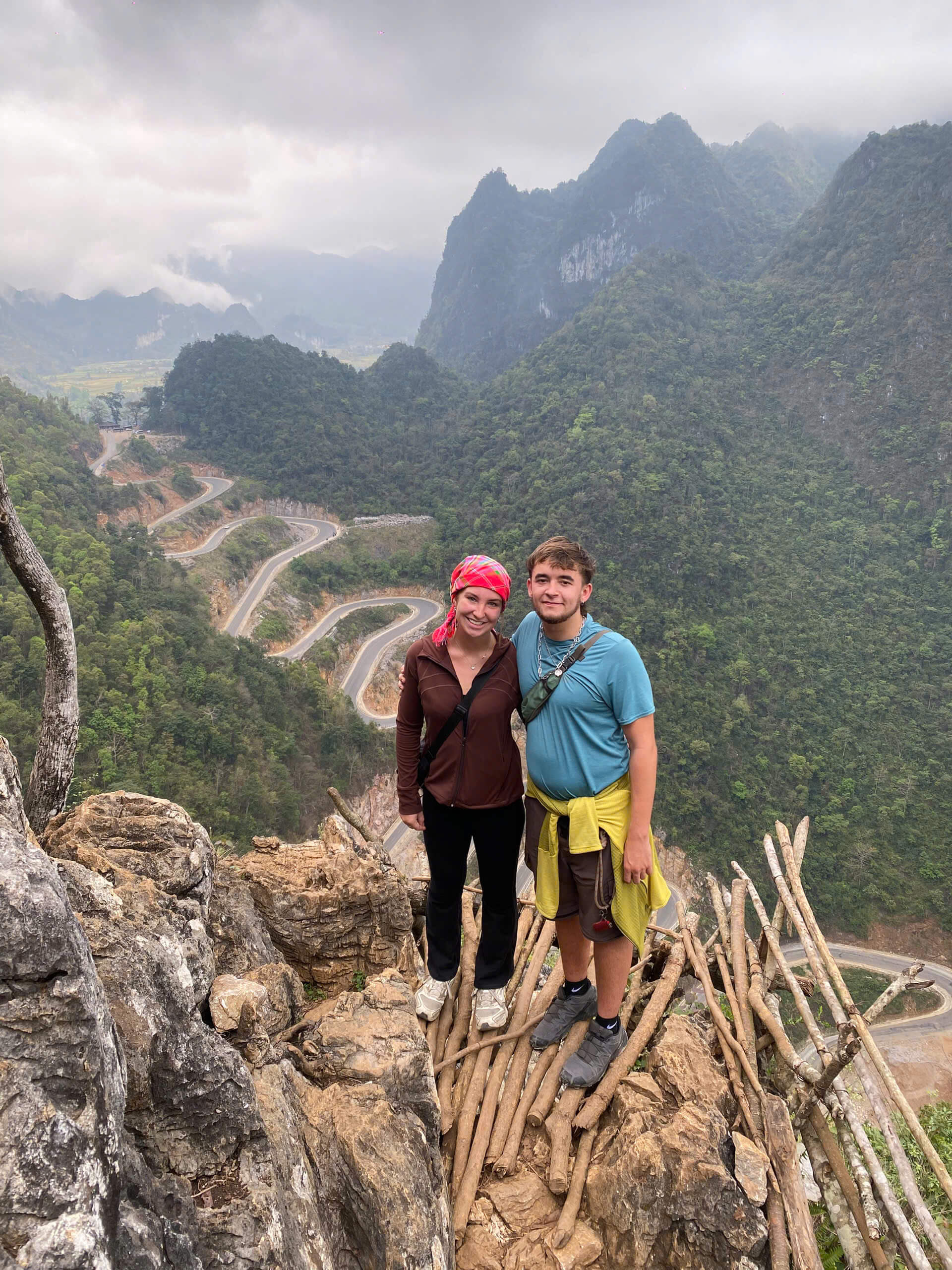 Tourists posing at the breathtaking viewpoint of the 14-tier Khau Coc Cha Pass during the Cao Bang motorbike loop.