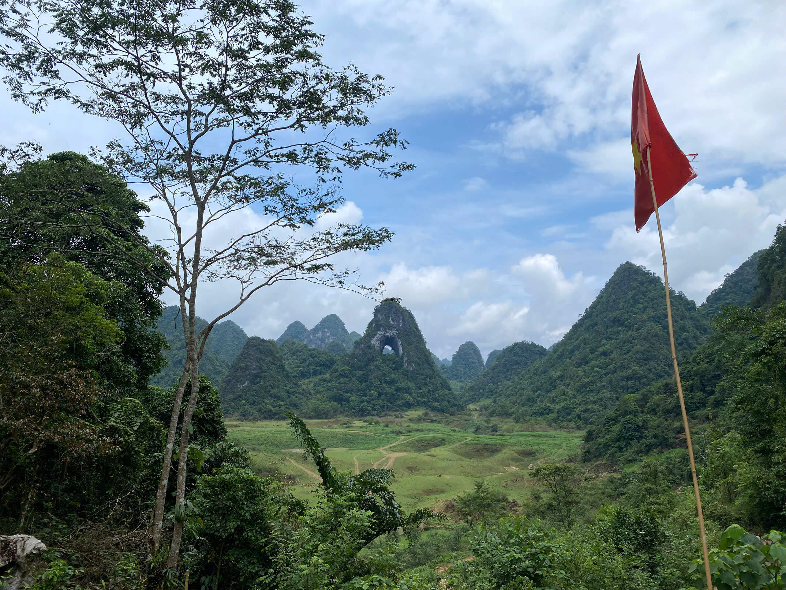 The famous God Eye Mountain and a waving Vietnam flag in a lush green valley in Cao Bang.